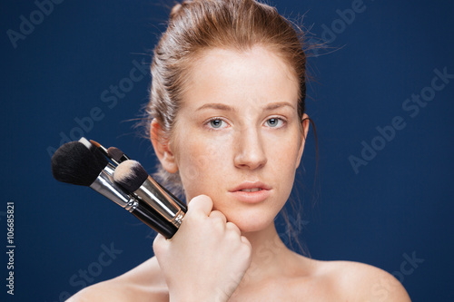 Young woman holding makeup brushes
