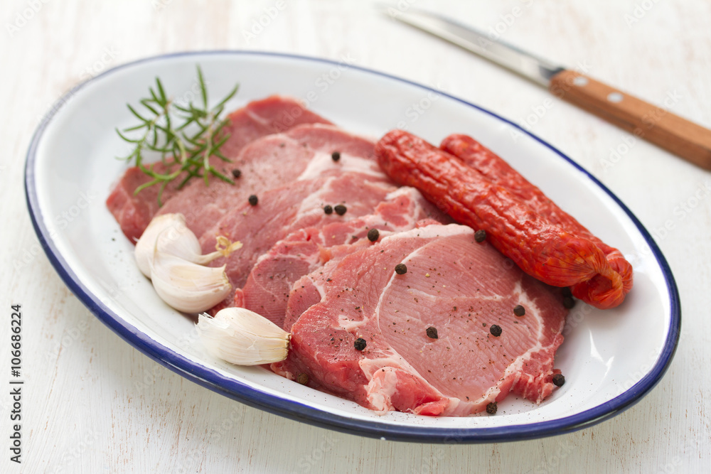 pork with black pepper, smoked sausages and garlic on dish and knife pork with black pepper, smoked sausages and garlic on dish and knife