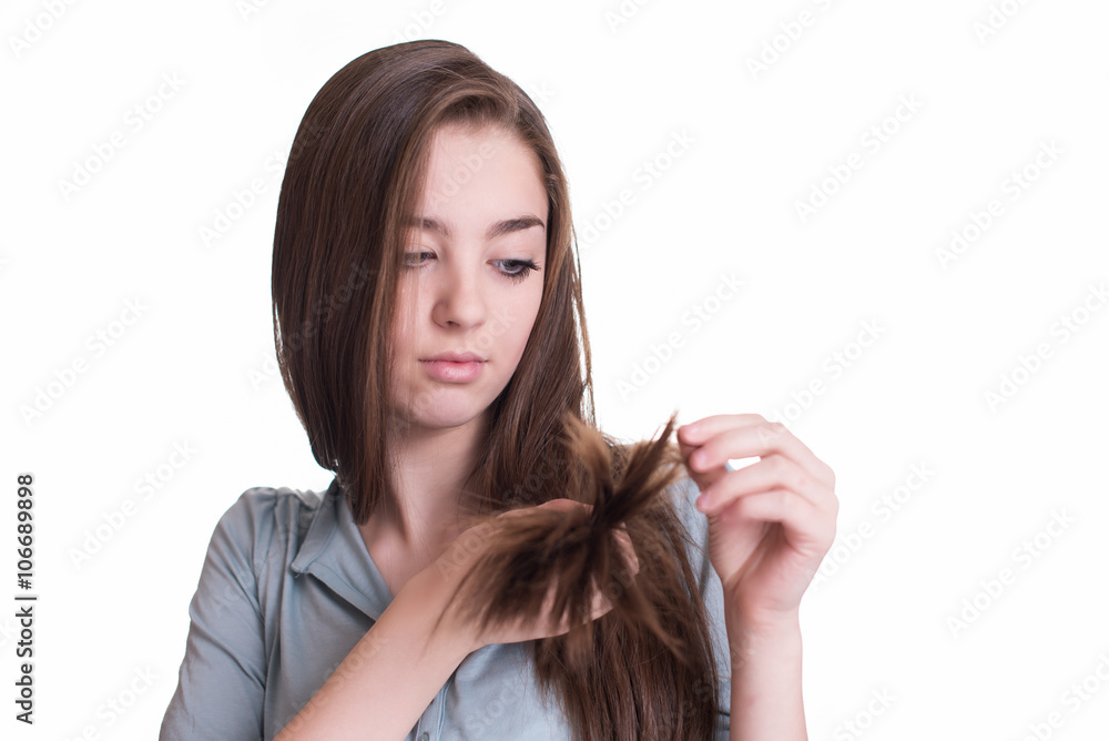 Young woman looking at split ends. Damaged long hair Young woman looking at split ends. Damaged long hair
