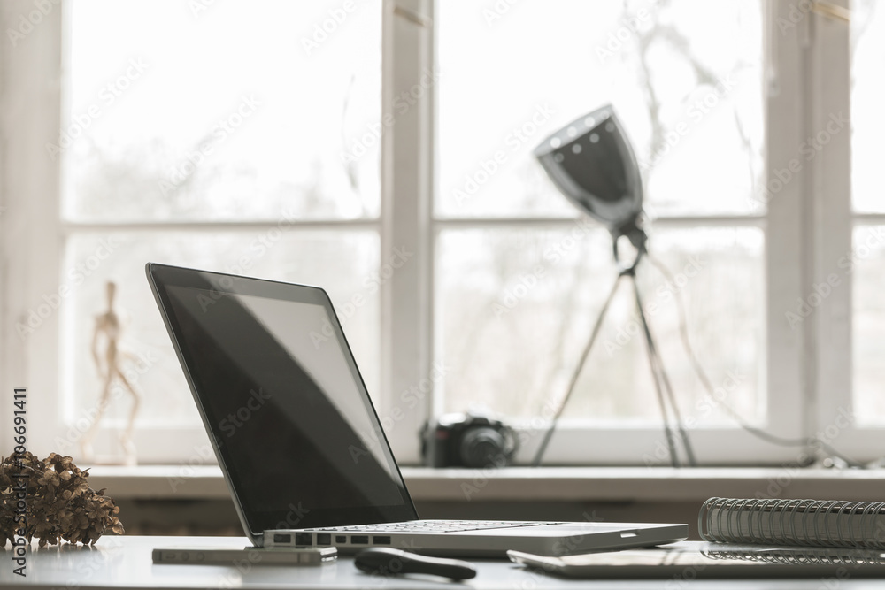 Creative workspace with big window in the background. Laptop and retro lamp.