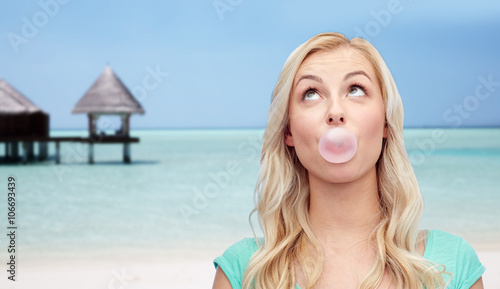 Fotografie happy woman or teenage girl chewing gum on beach