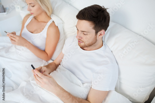 couple with smartphones in bed