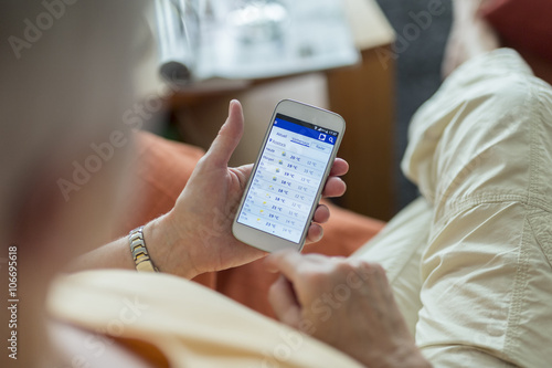 Senior woman looking at weather forecast on smartphone display