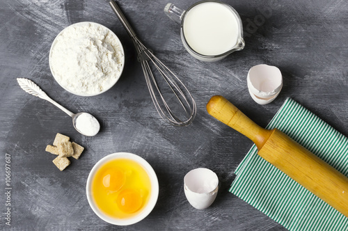 Ingredients for pastries: flour, eggs, milk against a dark backg