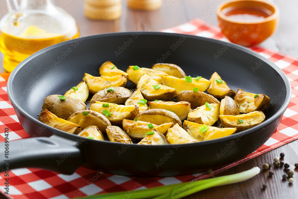 Fresh fried potato wedges with rosemary and spring onion on table Fresh fried potato wedges with rosemary and spring onion on table