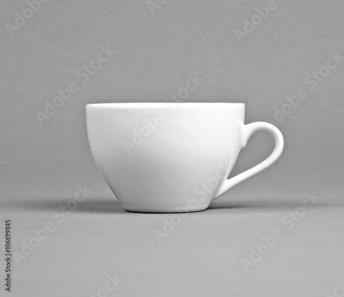 Small white coffee cup on a gray background.