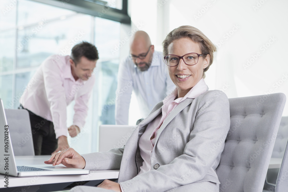 Three businesspeople with laptop in conference room Three businesspeople with laptop in conference room