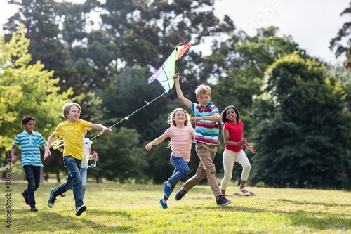 Cheerful children playing with kite in park photo