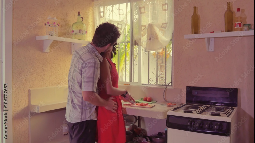 Hispanic woman cutting vegetables while man hugging her from behind in kitchen. 4k Hispanic woman cutting vegetables while man hugging her from behind in kitchen. 4k