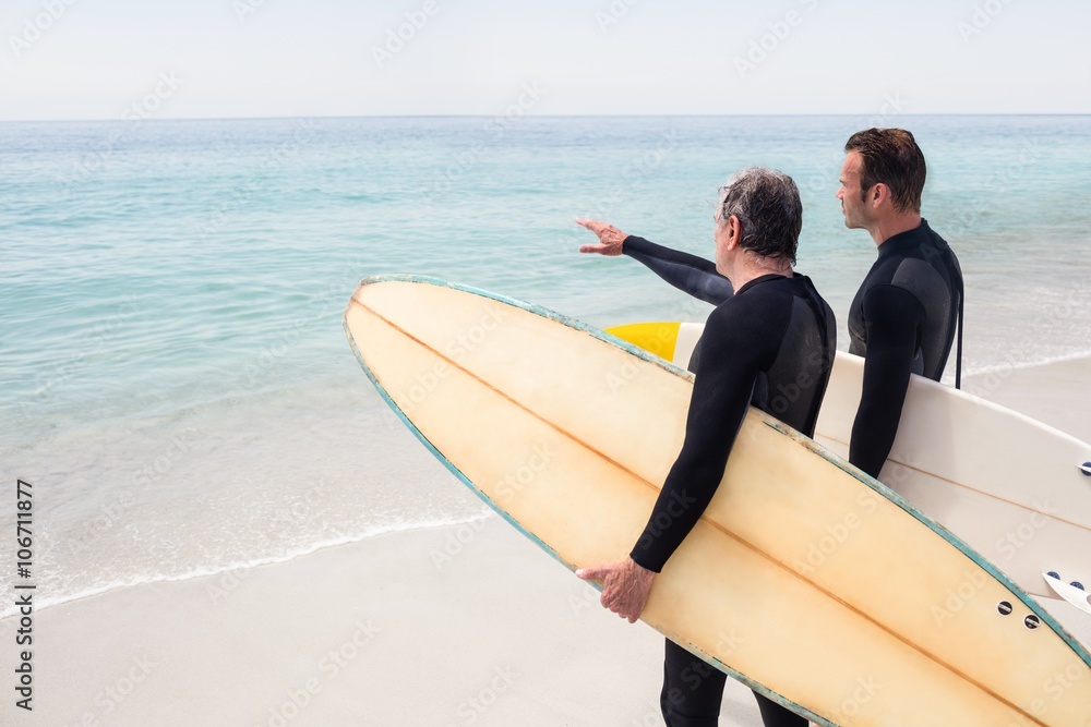 © Wavebreak Media - Father and son with surfboard pointing at a distance