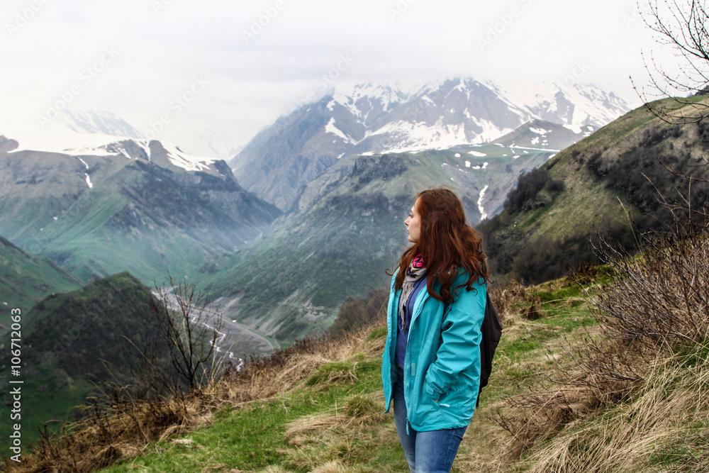 Young woman enjoying the view of Caucasian Mountains in Gudauri, Georgia. The majestic and beautiful mountains of the Caucasus