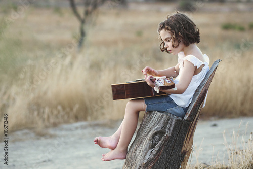 Girl sitting in a field playing the guitar