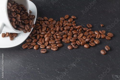 Cup with coffee beans on dark background