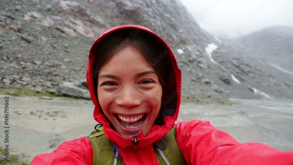 People having fun. Active outdoors hiker taking selfie using app on smartphone. Happy hiking girl with mobile phone outside in nature in rain. Girl on hike in mountains. People having fun. Active outdoors hiker taking selfie using app on smartphone. Happy hiking girl with mobile phone outside in nature in rain. Girl on hike in mountains.