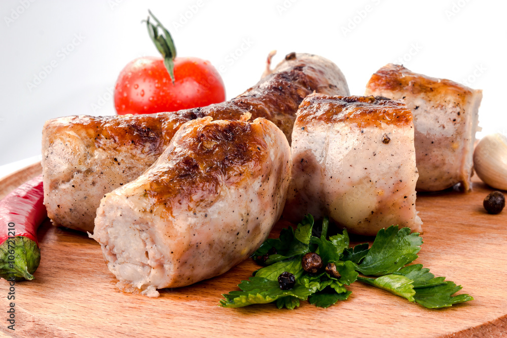 fried pork sausages on a barbecue on a wooden plate with cherry tomatoes and hot peppers fried pork sausages on a barbecue on a wooden plate with cherry tomatoes and hot peppers