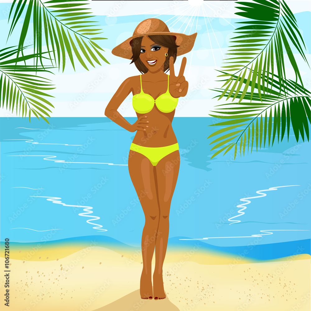 beautiful african american woman in bikini and big straw hat standing on tropical beach showing victory sign