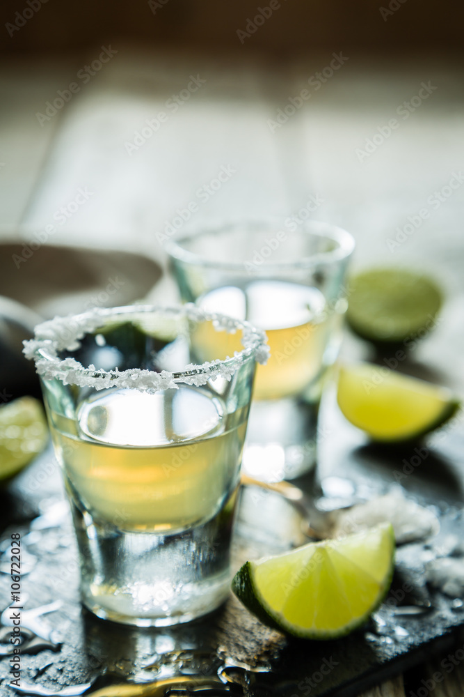 Gold tequila shots on rustic wood background Gold tequila shots on rustic wood background