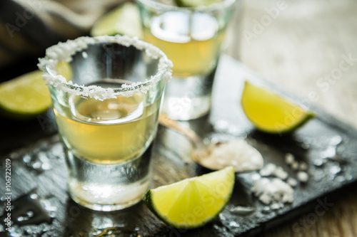 Gold tequila shots on rustic wood background