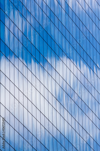Facade of glass and steel with open window reflecting sky and cl