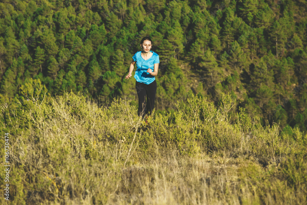 Young female jogger on the move in front of forest Young female jogger on the move in front of forest