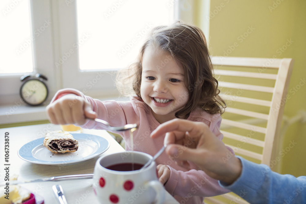 Portrait of little girl giving honey at her mother's tea Portrait of little girl giving honey at her mother's tea