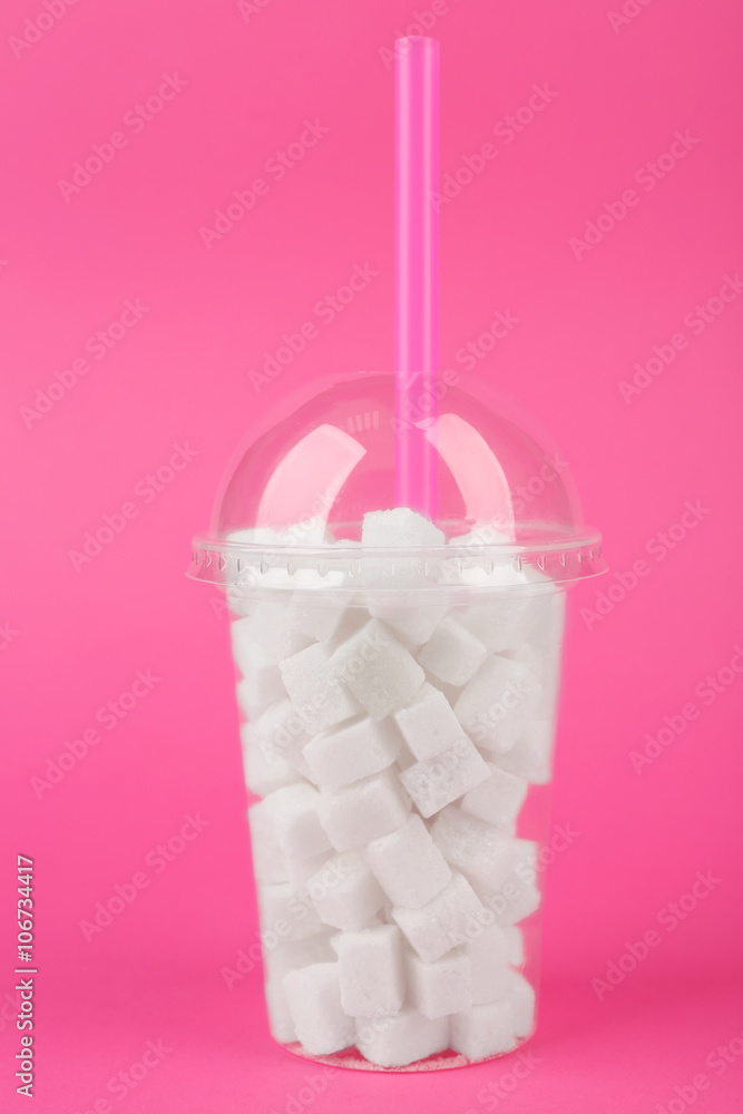 Plastic smoothie cup with lump sugar and cocktail tube on pink background Plastic smoothie cup with lump sugar and cocktail tube on pink background
