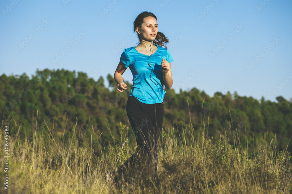 Young female jogger on the move in front of forest Young female jogger on the move in front of forest