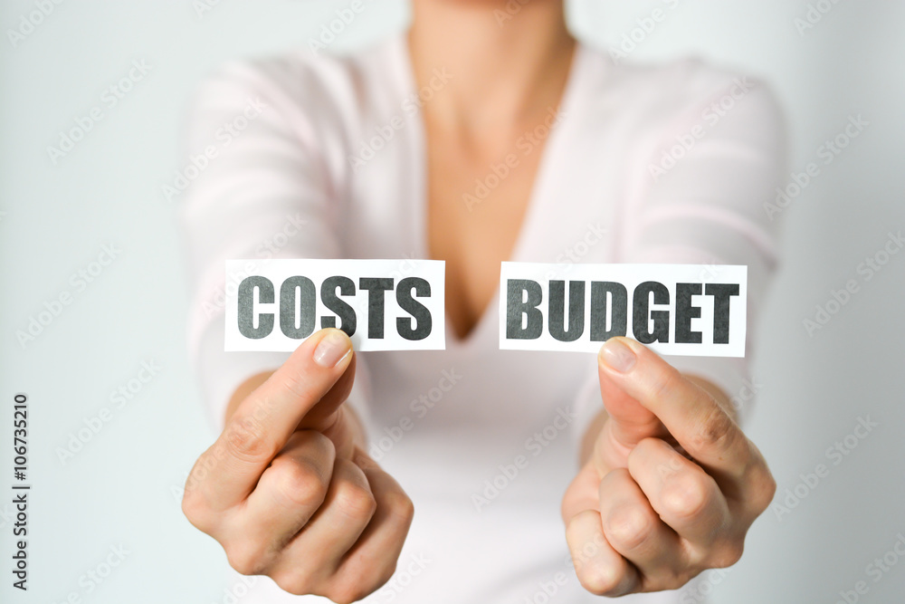 Budget planning concept with woman hands holding two printout with cost and budget words Budget planning concept with woman hands holding two printout with cost and budget words