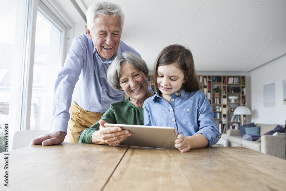 Grandparents and their granddaughter using digital tablet at home Grandparents and their granddaughter using digital tablet at home