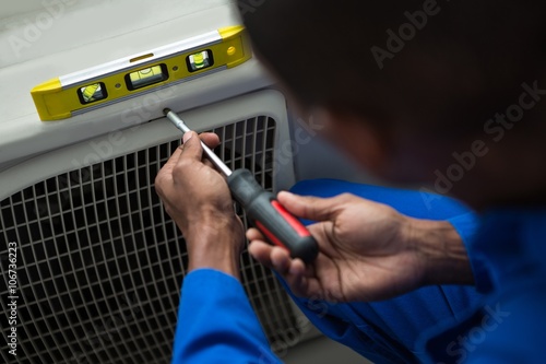 Handyman testing air conditioner with screwdriver