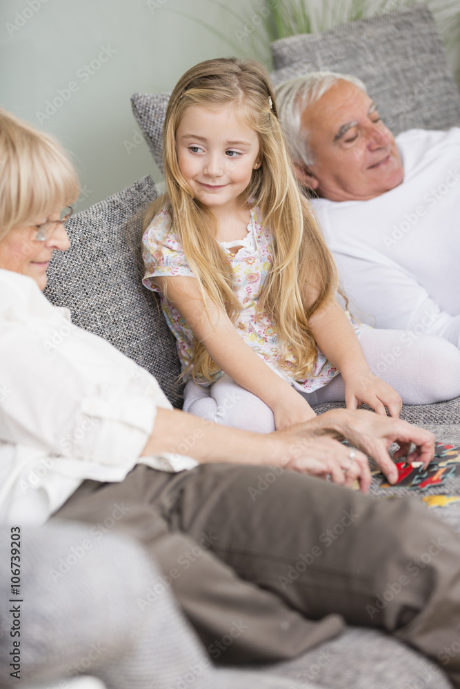 Senior woman and granddaughter playing together on sofa in living room Senior woman and granddaughter playing together on sofa in living room
