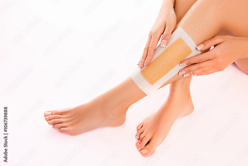 Fototapeta premium Woman using beeswax stripe to shave her leg, close up photo