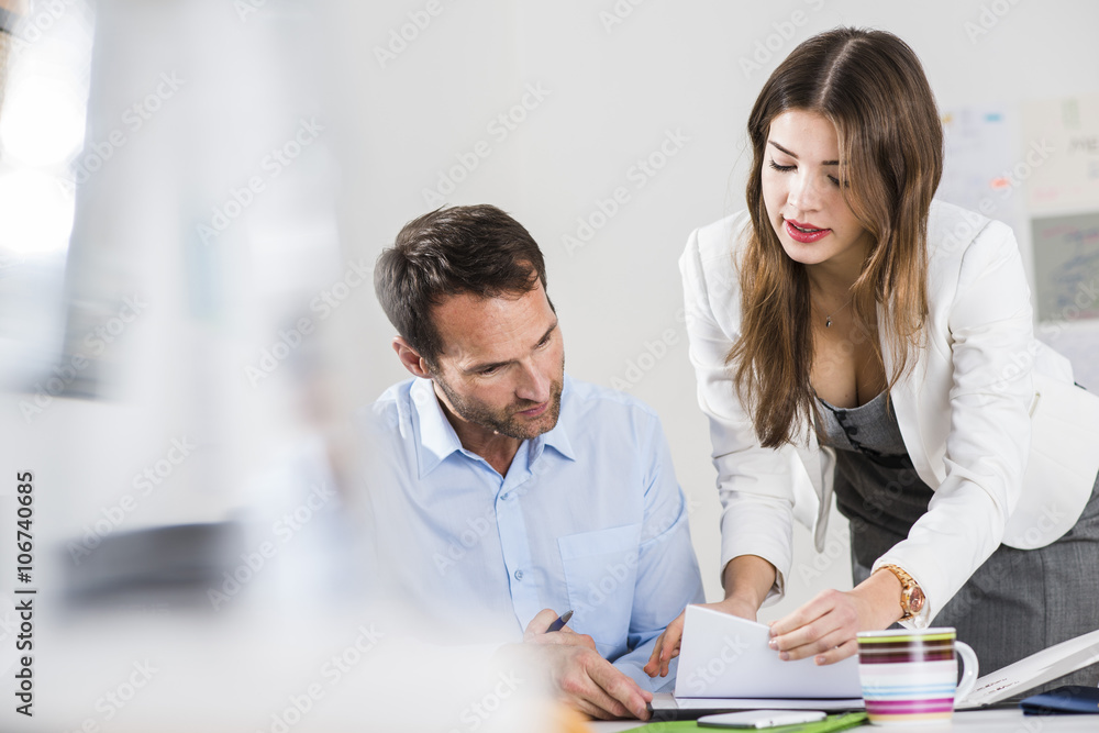 Businessman and secretary with file folder talking in office Businessman and secretary with file folder talking in office