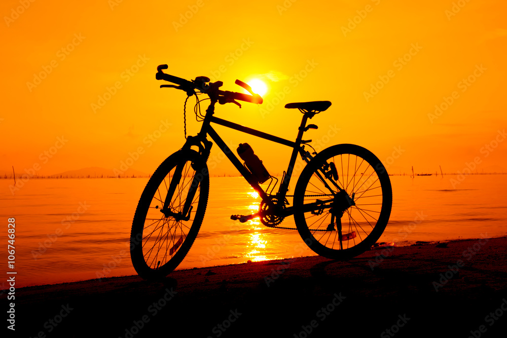 Fototapeta premium Silhouette of bicycle on the beach against colorful sunset in the sea. Outdoors.