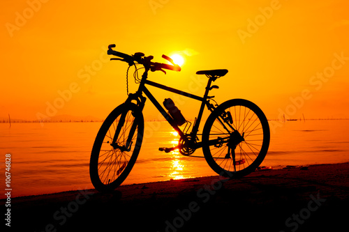 Silhouette of bicycle on the beach against colorful sunset in the sea. Outdoors.