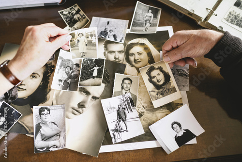 Hands of senior couple holding old photographs of themselves photo