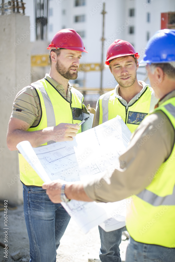 Construction workers discussing building plans in construction site Construction workers discussing building plans in construction site