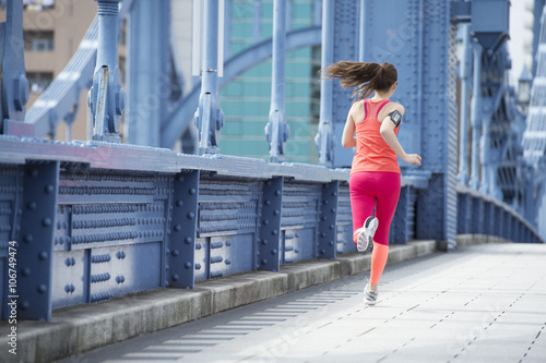 Back figure of a woman running on the bridge