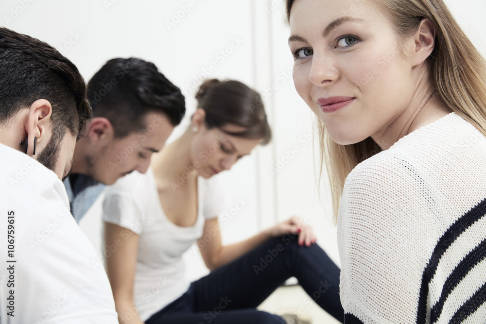 Smiling woman turning round with colleagues in background Smiling woman turning round with colleagues in background