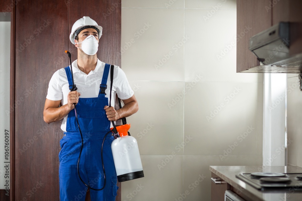 Front view of pest worker spraying in kitchen Front view of pest worker spraying in kitchen