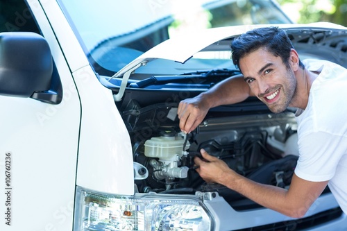 Portrait of happy mechanic fixing van