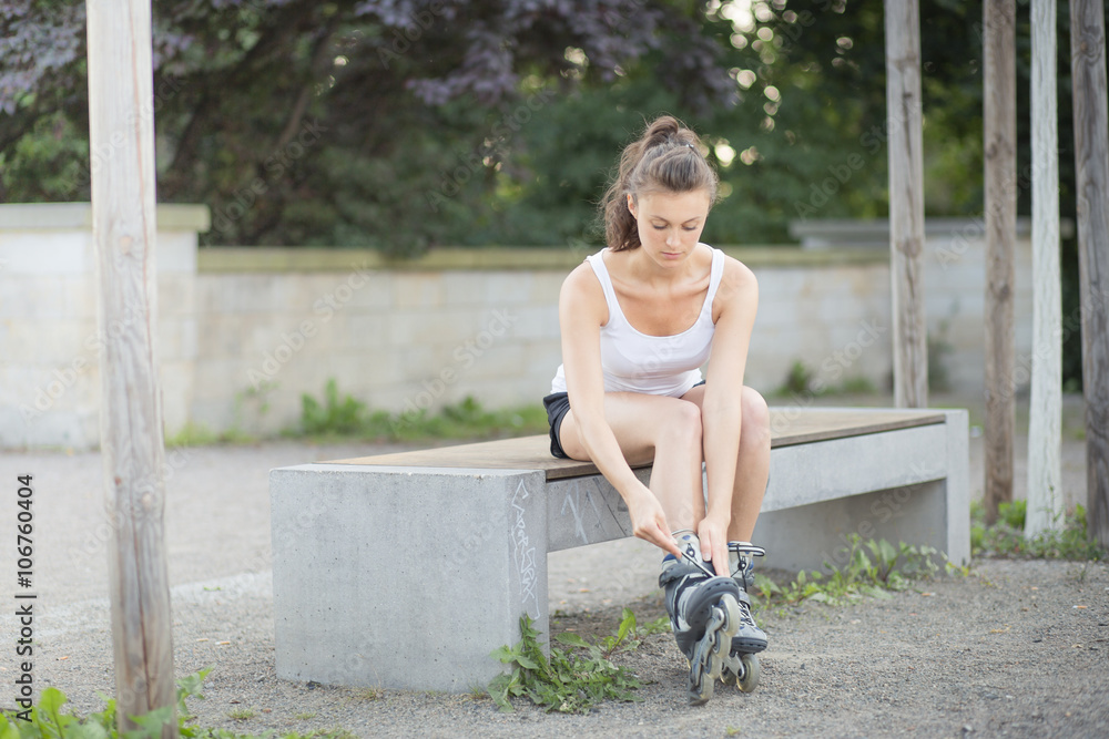 Junge Frau zieht sich Inlineskater an StockFoto Adobe Stock