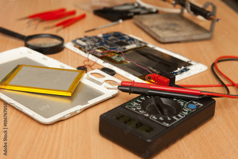 Disassembled tablet and tools on a wooden background. View from Disassembled tablet and tools on a wooden background. View from