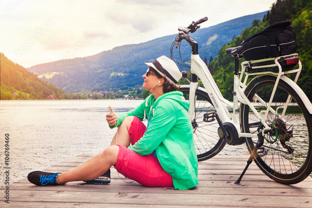 Fototapeta premium woman with e-bike resting beside a beautiful lake-e-power 18