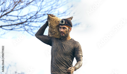 Participant in extreme obstacle race carrying sandbags