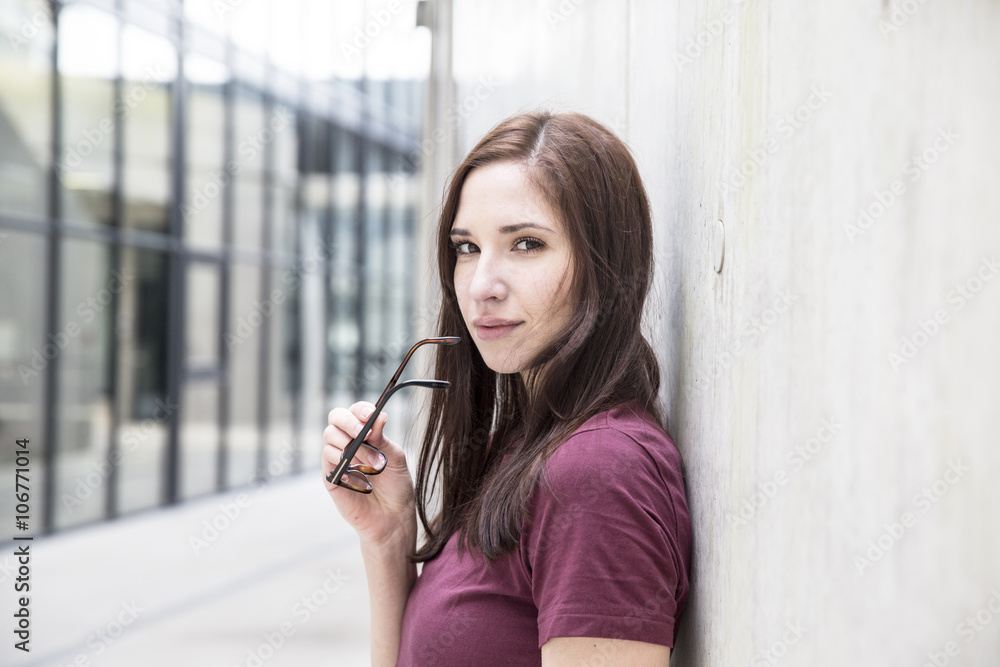 Portrait of young woman leaning against concrete wall Portrait of young woman leaning against concrete wall