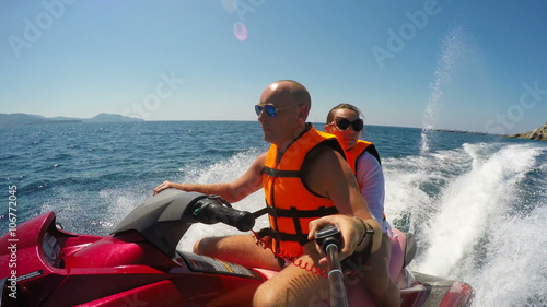Happy young caucasian couple riding jet ski on sea