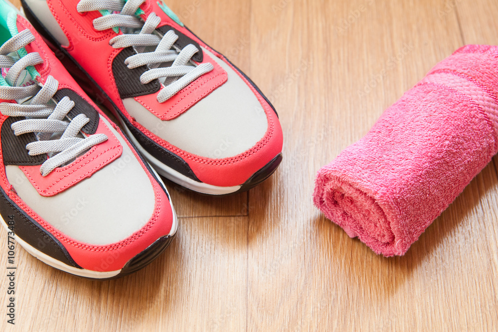 red and grey sneakers with grey shoelaces and red towel on wooden background indoors