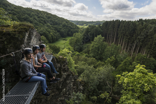 Germany, Westerwald, Hoelderstein, three friends on via ferrata having a break