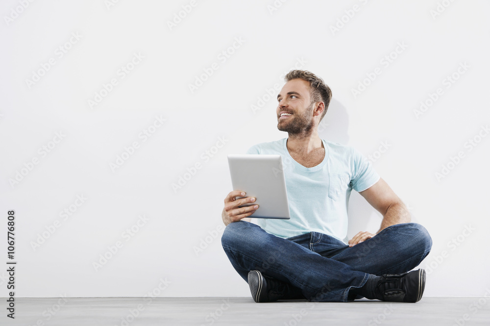 Portrait of young man sitting on floor holding tablet computer Portrait of young man sitting on floor holding tablet computer